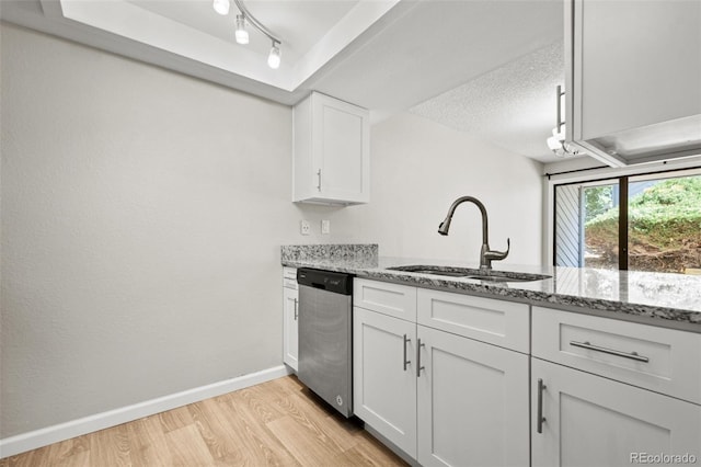 kitchen with dishwasher, white cabinetry, sink, and stone countertops