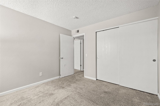 unfurnished bedroom featuring light colored carpet, a textured ceiling, and a closet