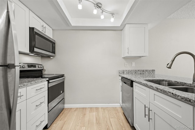 kitchen featuring light hardwood / wood-style floors, stainless steel appliances, light stone counters, white cabinets, and sink