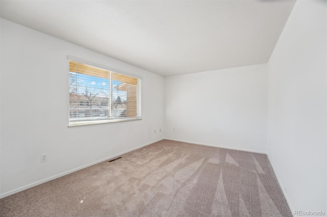 unfurnished room with light carpet, visible vents, and baseboards