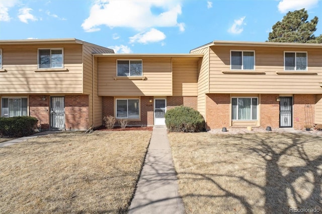 multi unit property with brick siding and a front lawn