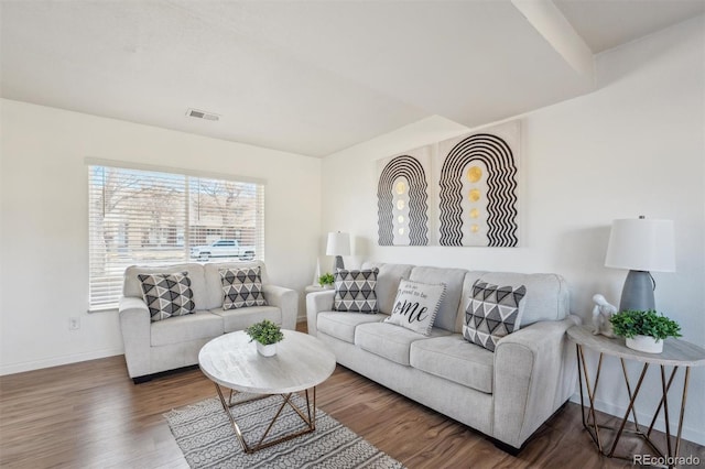 living area with wood finished floors, visible vents, and baseboards