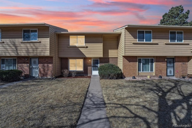 townhome / multi-family property featuring brick siding and a front lawn