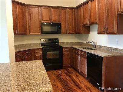 804 Summer Hawk Dr Unit 6105, Longmont, CO 80504 - kitchen featuring black appliances, dark wood-style flooring, and light stone countertops