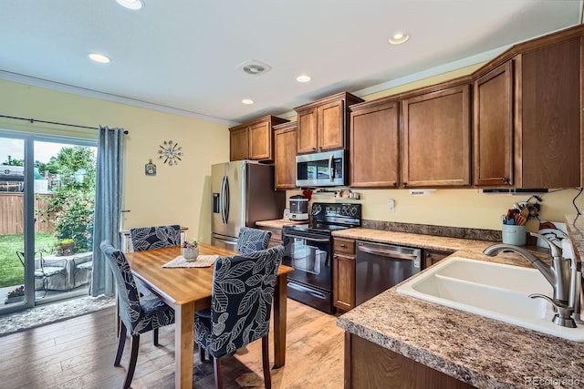 24748 E Layton Pl, Aurora, CO 80016 - kitchen with stainless steel appliances, ornamental molding, recessed lighting, light wood finished floors, and brown cabinetry
