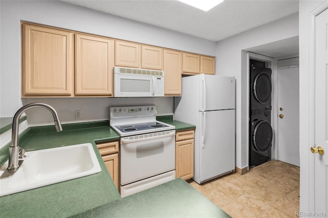 kitchen with dark countertops, light brown cabinetry, a sink, stacked washing maching and dryer, and white appliances