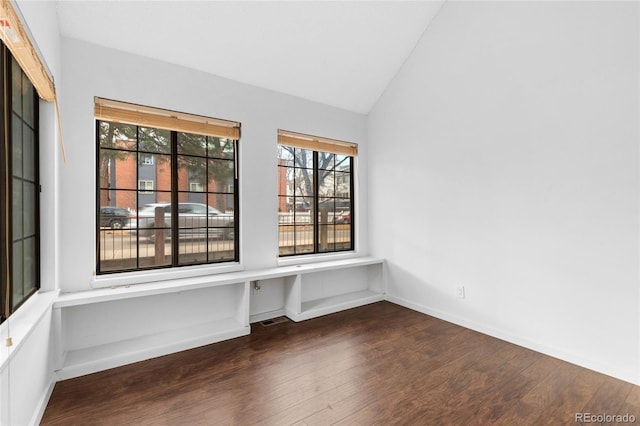 unfurnished room featuring vaulted ceiling, dark wood-style flooring, a wealth of natural light, and baseboards