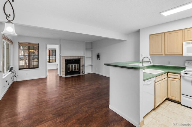 kitchen featuring white appliances, dark countertops, open floor plan, decorative light fixtures, and a peninsula