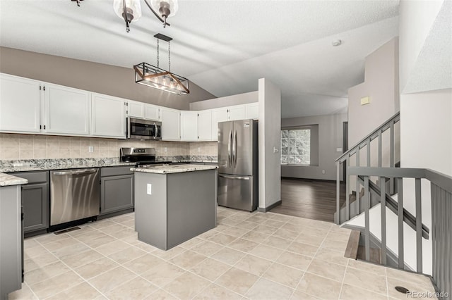 10172 Woodrose Ln, Highlands Ranch, CO 80129 - kitchen featuring stainless steel appliances, vaulted ceiling, tasteful backsplash, a center island, and light tile patterned floors