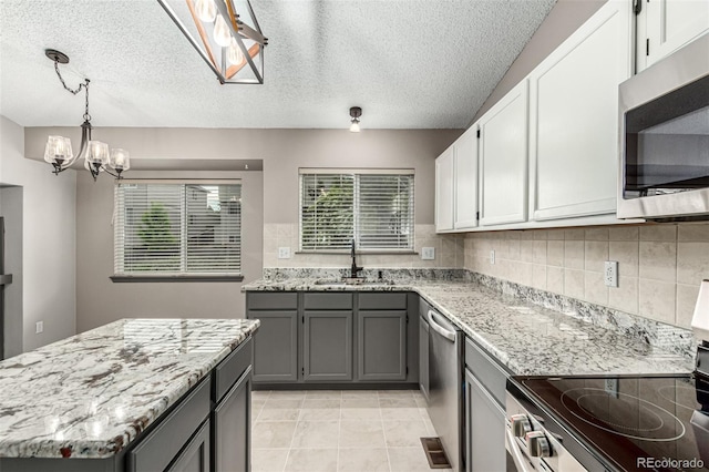 10172 Woodrose Ln, Highlands Ranch, CO 80129 - kitchen with appliances with stainless steel finishes, backsplash, light stone counters, a textured ceiling, and a chandelier