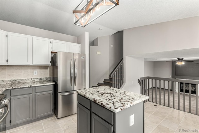 10172 Woodrose Ln, Highlands Ranch, CO 80129 - kitchen with stainless steel appliances, a ceiling fan, a kitchen island, light stone countertops, and vaulted ceiling