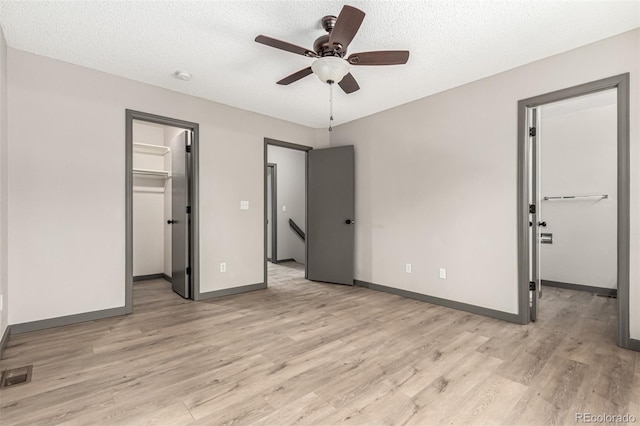 10172 Woodrose Ln, Highlands Ranch, CO 80129 - unfurnished bedroom featuring a spacious closet, a closet, light wood-style floors, ceiling fan, and a textured ceiling