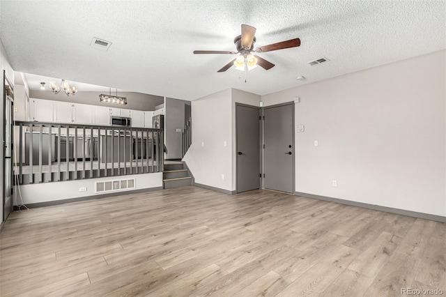 10172 Woodrose Ln, Highlands Ranch, CO 80129 - unfurnished living room featuring ceiling fan, a textured ceiling, light wood finished floors, stairway, and a chandelier