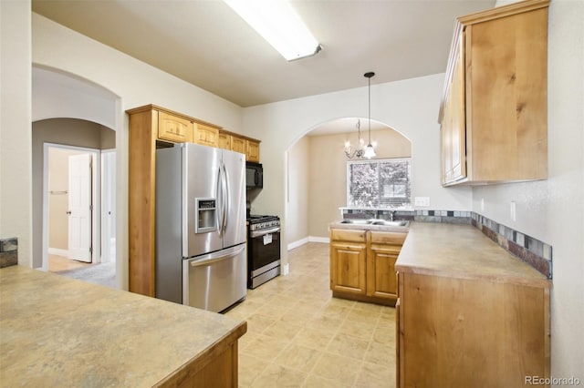 kitchen featuring decorative light fixtures, a notable chandelier, appliances with stainless steel finishes, and sink