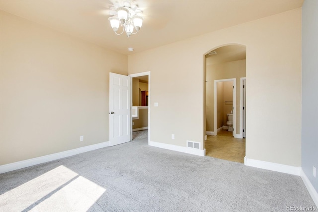 unfurnished bedroom featuring light carpet and connected bathroom