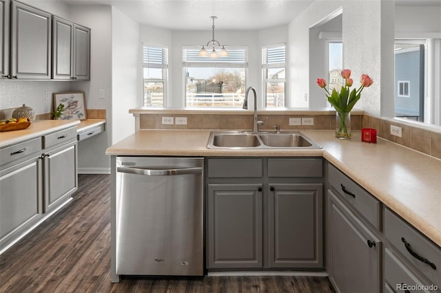 kitchen featuring dark hardwood / wood-style floors, dishwasher, sink, gray cabinetry, and hanging light fixtures