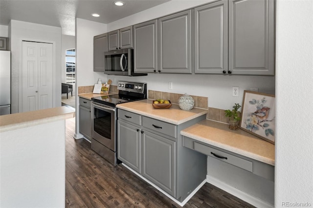 kitchen featuring stainless steel appliances, dark hardwood / wood-style flooring, and gray cabinetry