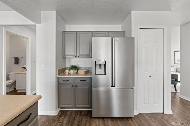 kitchen with gray cabinetry, a textured ceiling, dark hardwood / wood-style flooring, and stainless steel fridge with ice dispenser