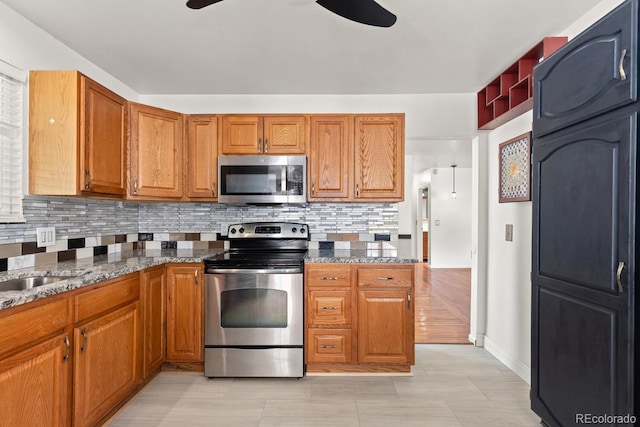 4627 S Norfolk Way, Aurora, CO 80015 - kitchen with appliances with stainless steel finishes, a ceiling fan, backsplash, brown cabinetry, and dark stone counters