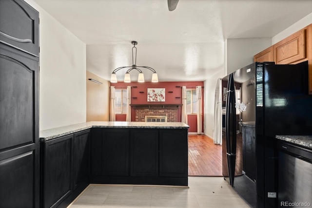 4627 S Norfolk Way, Aurora, CO 80015 - kitchen with light stone counters, a peninsula, pendant lighting, a brick fireplace, and freestanding refrigerator
