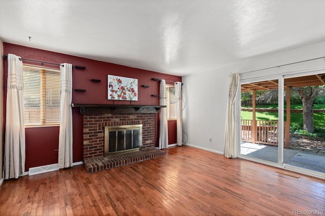 4627 S Norfolk Way, Aurora, CO 80015 - unfurnished living room featuring plenty of natural light, wood-type flooring, and a brick fireplace