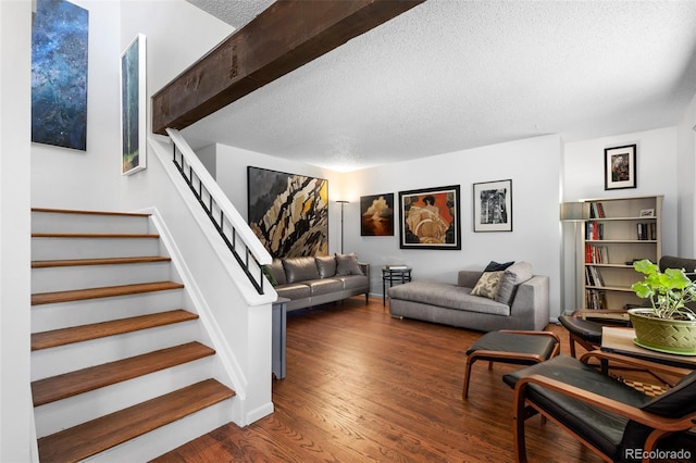 living room featuring stairway, a textured ceiling, baseboards, and wood finished floors