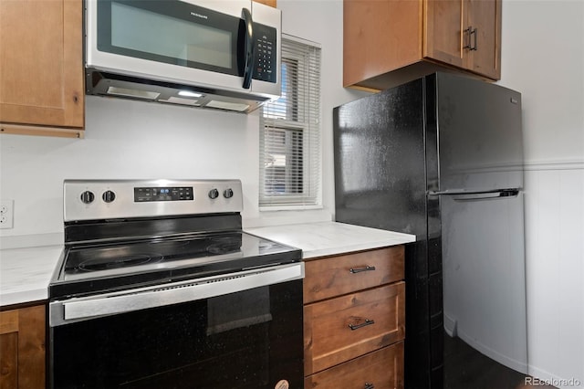 kitchen featuring light countertops, appliances with stainless steel finishes, and brown cabinetry