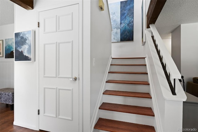 stairs with a textured ceiling and wood finished floors