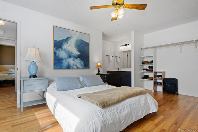 bedroom featuring connected bathroom, light wood-style flooring, and ceiling fan
