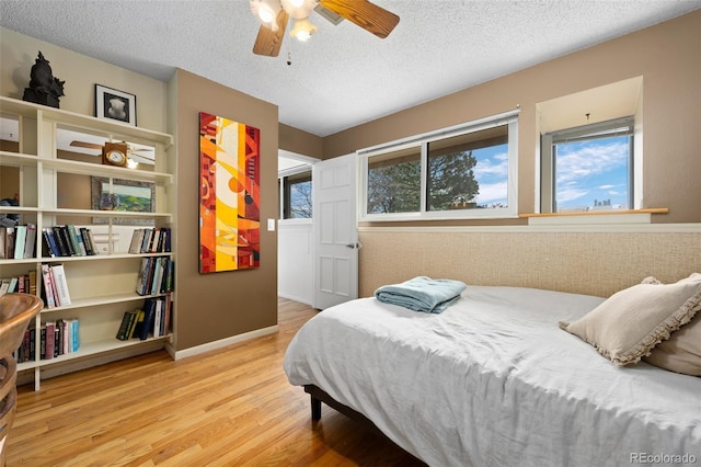 bedroom featuring a ceiling fan, a textured ceiling, wood finished floors, and baseboards