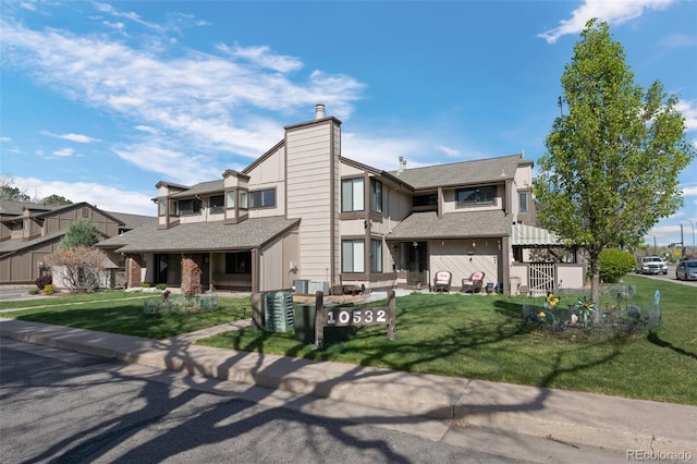 view of front of home with a front lawn, a chimney, and central air condition unit