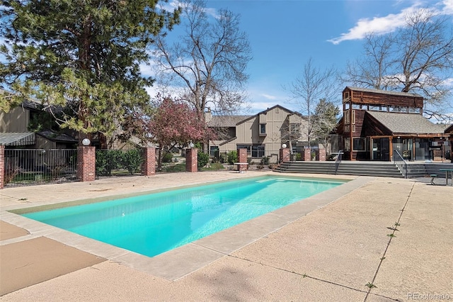 view of swimming pool with a residential view, a patio, a fenced in pool, and fence