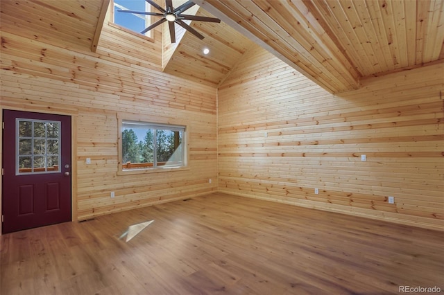 empty room with high vaulted ceiling, a ceiling fan, wood finished floors, wooden walls, and wood ceiling