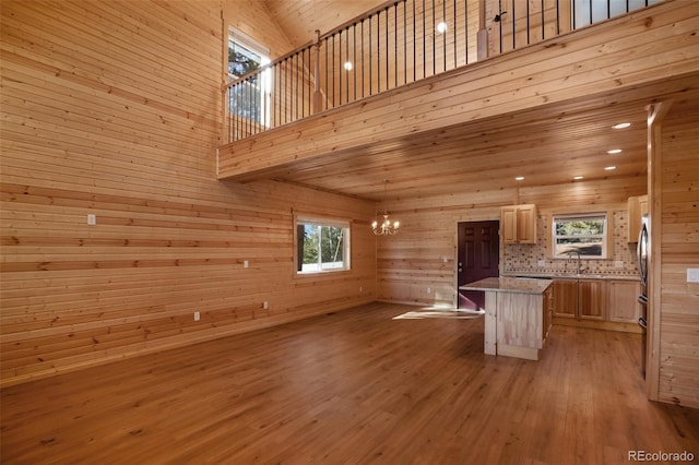 interior space featuring recessed lighting, light wood-style flooring, an inviting chandelier, a towering ceiling, and a sink