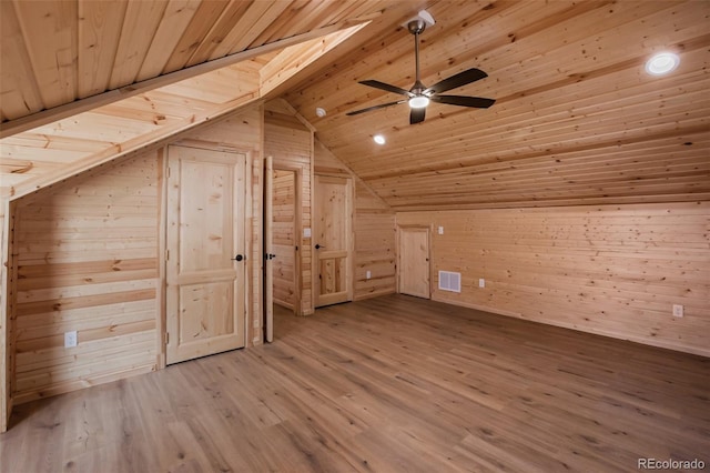 additional living space featuring wooden walls, wood finished floors, visible vents, vaulted ceiling, and wooden ceiling