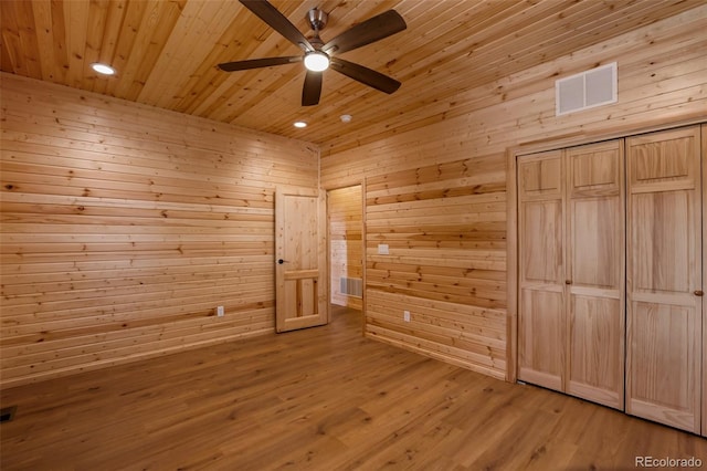 unfurnished bedroom with visible vents, light wood-style floors, wood ceiling, and wooden walls