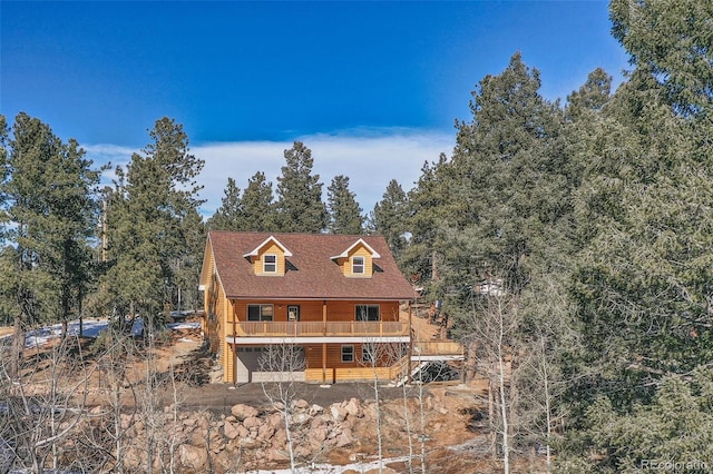 view of front of property with a garage, a deck, and faux log siding