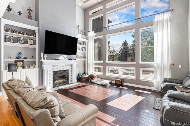 6940 Saddleback Ave, Firestone, CO 80504 - living area featuring a towering ceiling, a stone fireplace, wood finished floors, and built in features