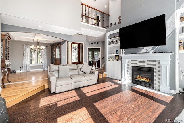 6940 Saddleback Ave, Firestone, CO 80504 - living area with a chandelier, wood finished floors, arched walkways, ornate columns, and a fireplace with flush hearth