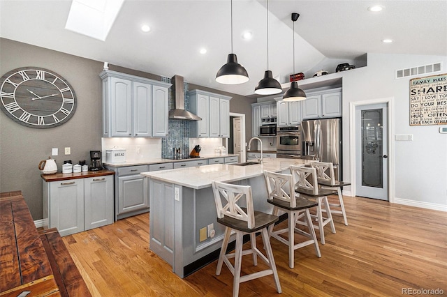 6940 Saddleback Ave, Firestone, CO 80504 - kitchen with wall chimney exhaust hood, lofted ceiling, stainless steel appliances, a sink, and gray cabinetry