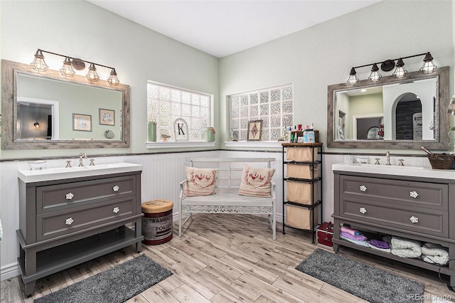 6940 Saddleback Ave, Firestone, CO 80504 - bathroom with two vanities, wood finished floors, and a wainscoted wall