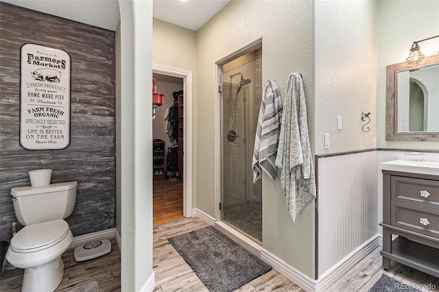6940 Saddleback Ave, Firestone, CO 80504 - bathroom with vanity, wood finished floors, a shower stall, a spacious closet, and toilet