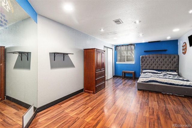 6940 Saddleback Ave, Firestone, CO 80504 - bedroom with wood finished floors, a textured wall, baseboards, recessed lighting, and a textured ceiling