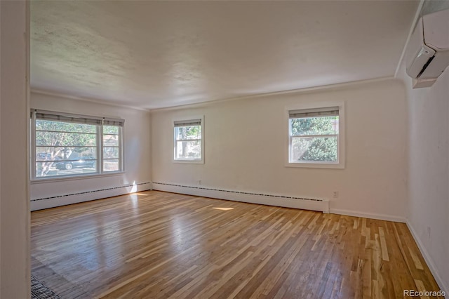 empty room with a baseboard radiator, light wood-type flooring, and a wall unit AC