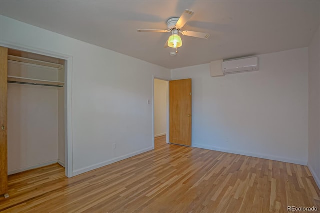 unfurnished bedroom with a closet, light hardwood / wood-style floors, a wall mounted AC, and ceiling fan