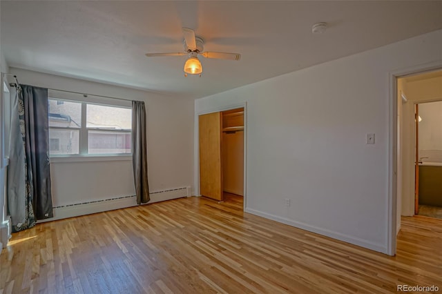 unfurnished bedroom with a closet, baseboard heating, light wood-type flooring, and ceiling fan