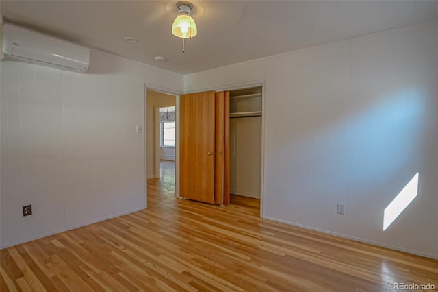 unfurnished bedroom featuring a closet, light hardwood / wood-style floors, a wall mounted AC, and ceiling fan