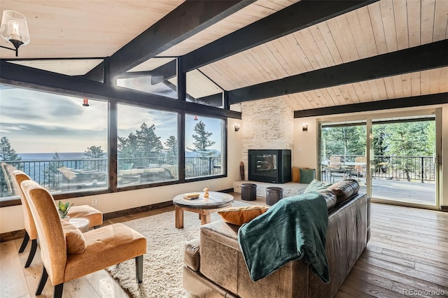 living area featuring a fireplace, lofted ceiling with beams, baseboards, and wood-type flooring