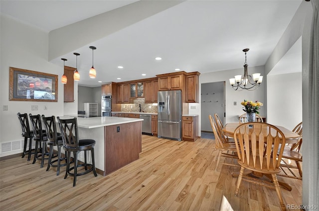 723 Orion Dr, Colorado Springs, CO 80906 - kitchen with appliances with stainless steel finishes, light wood finished floors, brown cabinetry, a peninsula, and recessed lighting