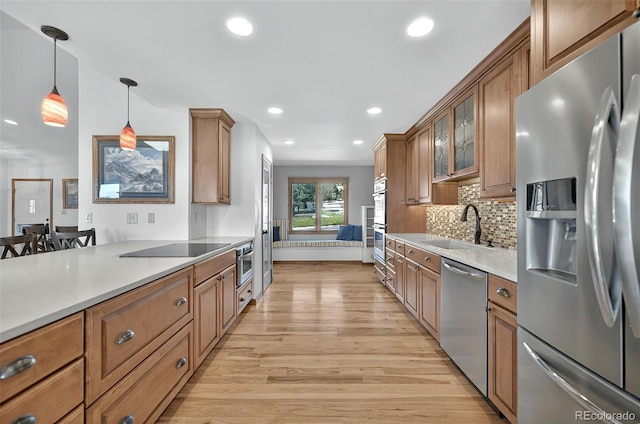 723 Orion Dr, Colorado Springs, CO 80906 - kitchen with appliances with stainless steel finishes, a sink, brown cabinetry, light wood-style floors, and hanging light fixtures